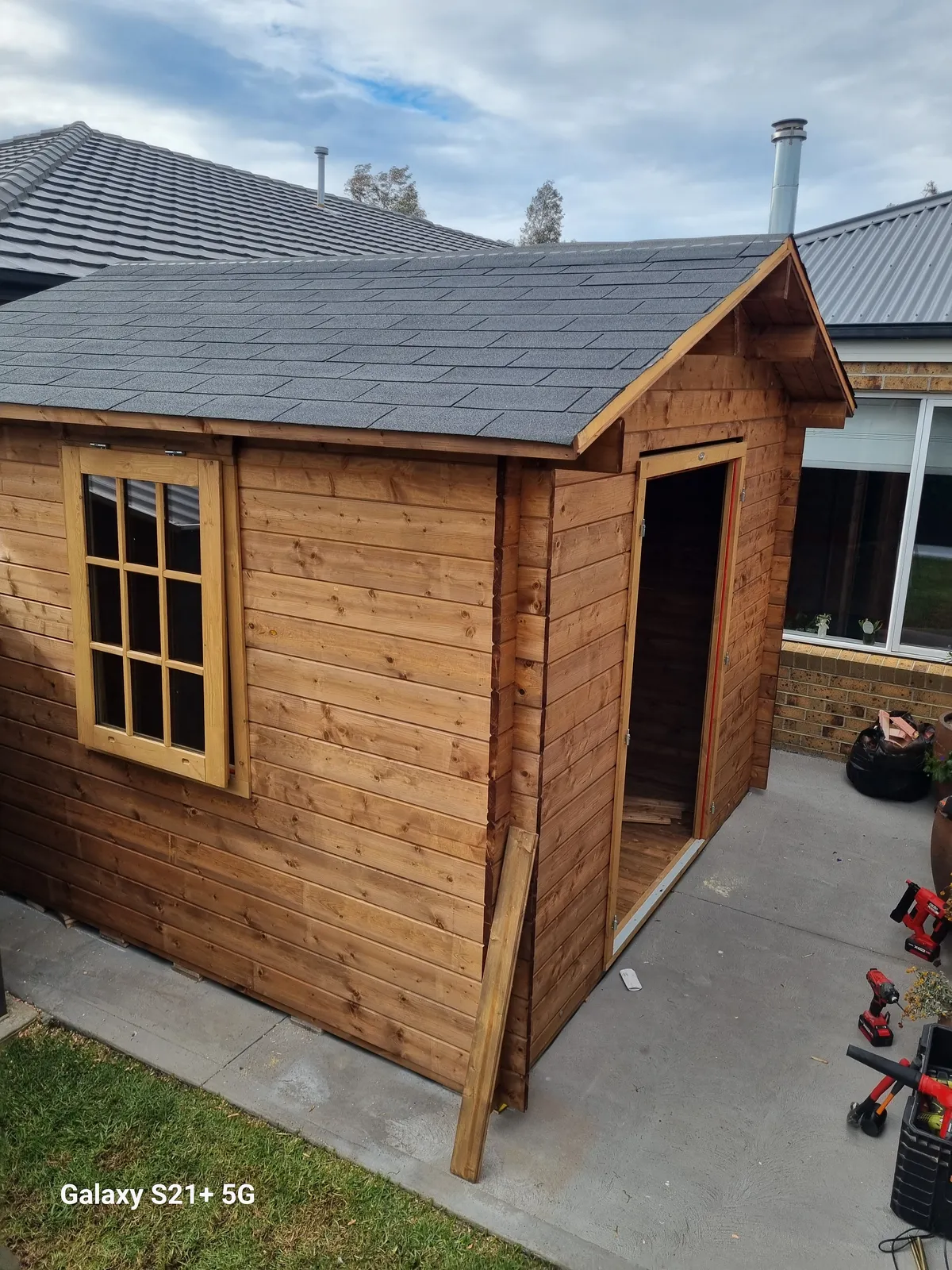 Cabin shell complete with shingled roof, window installed, ready for paint