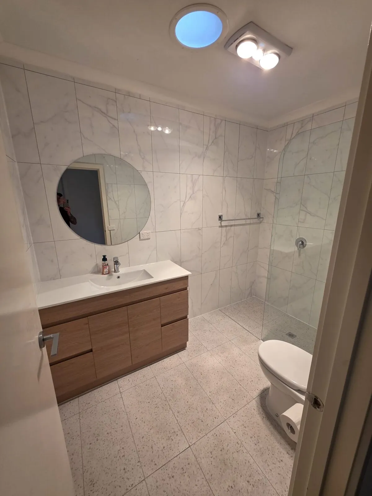Finished bathroom with round mirror, timber vanity, and frameless walk-in shower